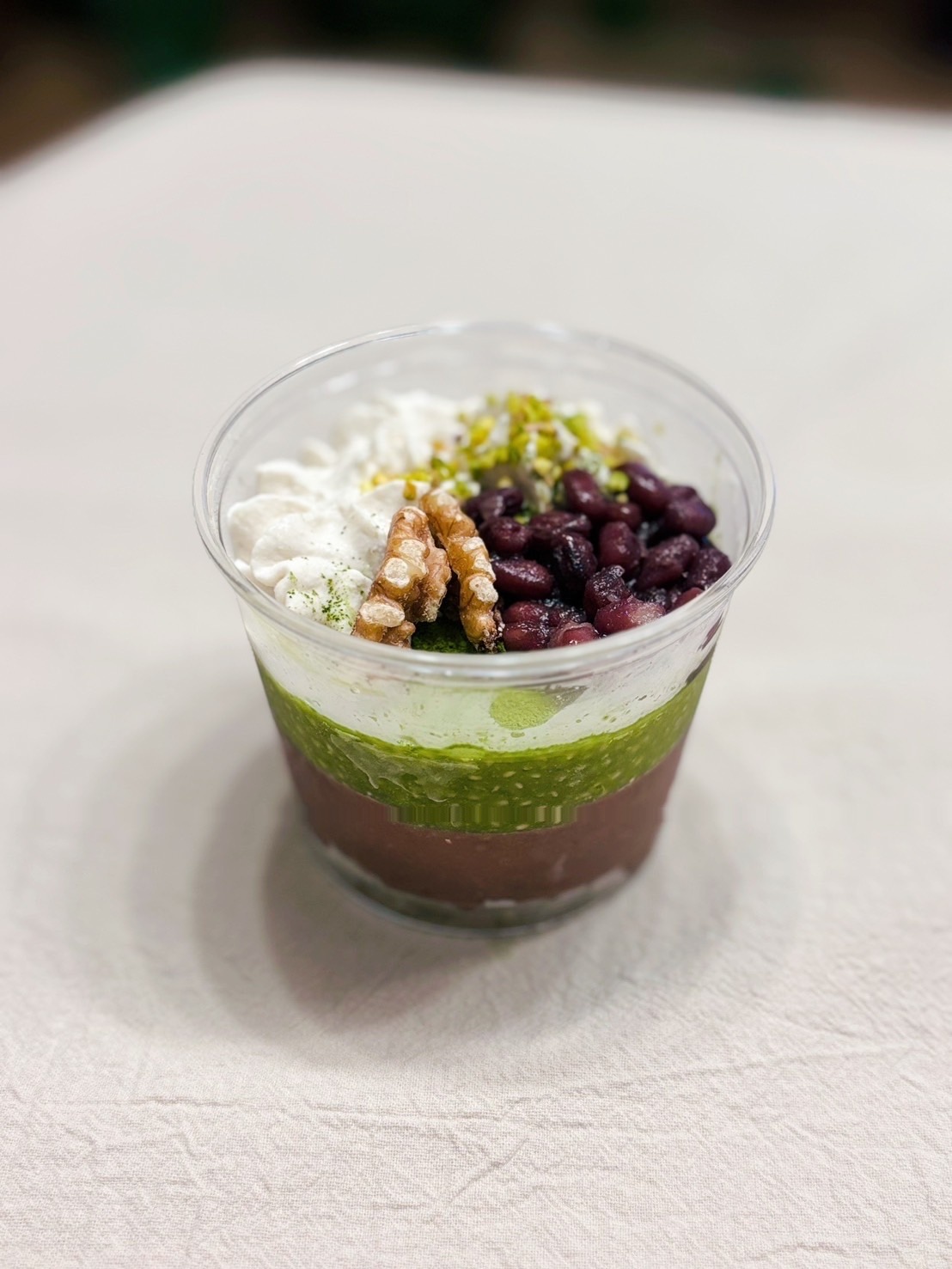 層になった抹茶のローケーキ — 抹茶チア、ココナッツホイップ、小豆、ピスタチオ